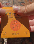 Unboxing and displaying the rough-cut, eco-friendly natural PURIFY shampoo bar from its light orange box packaging.