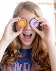 Image of a young woman playfully holding a pair of Everything Salve tins up to her eyes like binoculars.