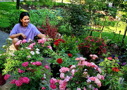 Komoni founder in her garden with an abundance of flowers. 