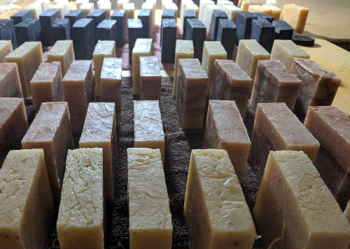 Various FACE & BODY CLEANSER BARS shown curing after being cut into bars. 