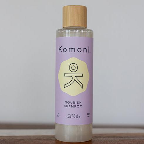 Wood top 8 oz. pastel-purple bottle of Nourish Botanical Shampoo with lavender and other essential oils for all hair types.