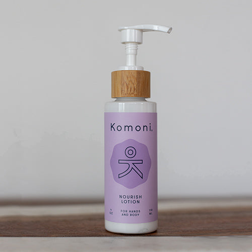 Wood top 4 oz. pastel purple pump-bottle of NOURISH Pure Botanicals &amp; Essential Oils body lotion.