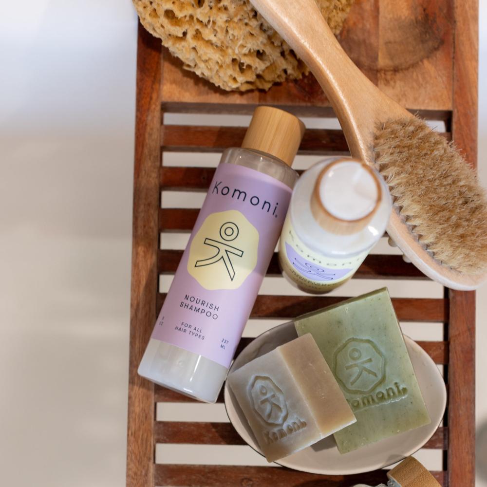 Nourish Lavender Shampoo and Conditioner shown with a Shampoo Bar and Face &amp; Body Cleanser Bar with other items like a sponge and bath brush. 