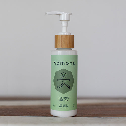 Wood top 4 oz. pastel green pump-bottle of RESTORE Pure Botanicals & Essential Oils body lotion. 