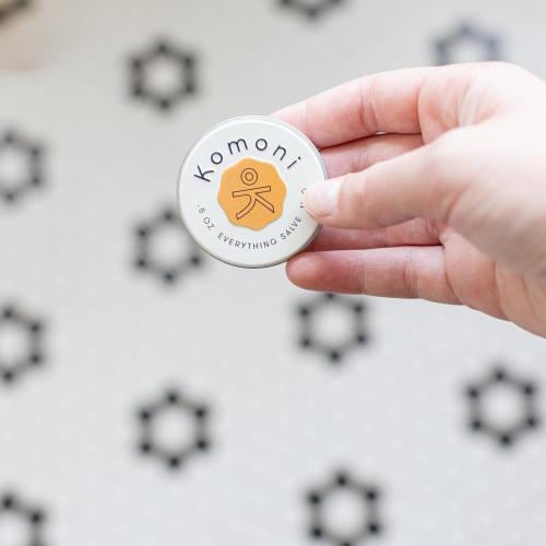 Pocket-sized salve held in fingertips fits comfortably in the palm of your hand.