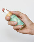 A hand shown holding a spray 2 oz. bottle of Four Thieves E3 rated hand sanitizer formulated with 65% ethyl alcohol to effectively kill harmful germs and bacteria, it also contains moisturizing hempseed oil, which helps the skin retain hydration, reduce inflammation, and improve texture. The antioxidant properties support the skin’s barrier, protecting it from environmental damage while leaving your hands soft and smooth. 