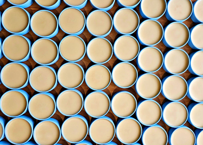 Freshly filled, sky-blue tins of BREATHE Everything Salve shown looking directly down from the top.