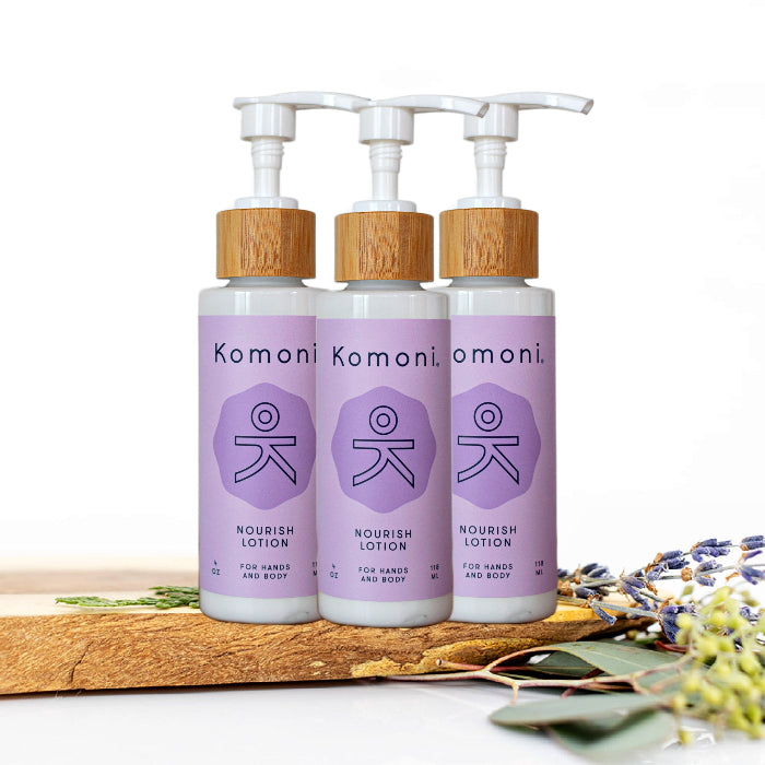 3 Wood top 4 oz. pastel purple pump-bottles of NOURISH pure botanicals & essential oils body lotion.