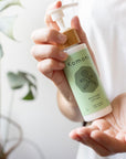 Pair of hands holding a light green pump bottle of Restore Botanical lotion with bamboo wood top