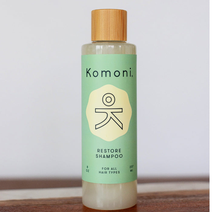 Wood top 8 oz. pastel-green bottle of Restore Botanical Shampoo with rosemary and other essential oils for all hair types.