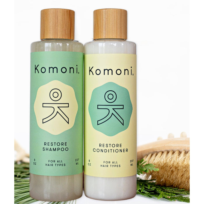 Wood top 8 oz. pastel green & yellow bottles of Restore Botanical Shampoo & Condition with rosemary and other essential oils for all hair types.