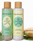 Wood top 8 oz. pastel green & yellow bottles of Restore Botanical Shampoo & Condition with rosemary and other essential oils for all hair types.