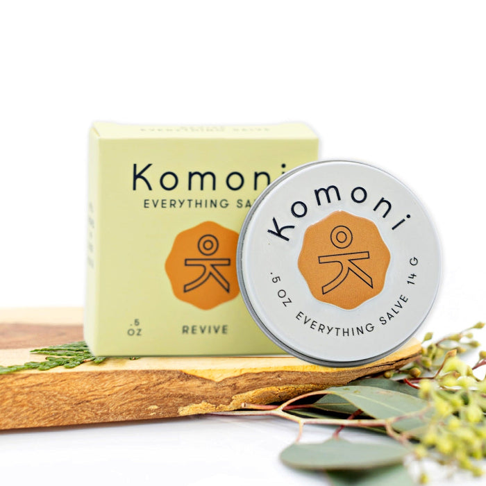 Lemongrass and orange essential oil REVIVE everything lips, hands, skin salve shown in tin in front of box. 