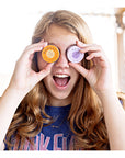 Image of a young woman playfully holding a pair of Everything Salve tins up to her eyes like binoculars.