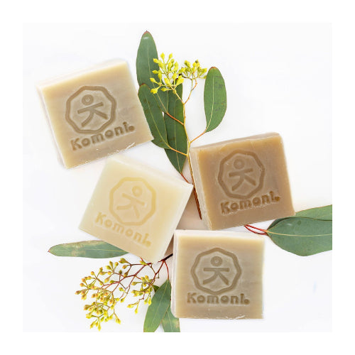 Four square shampoo bars playfully arranged on a background of natural plant ingredients.